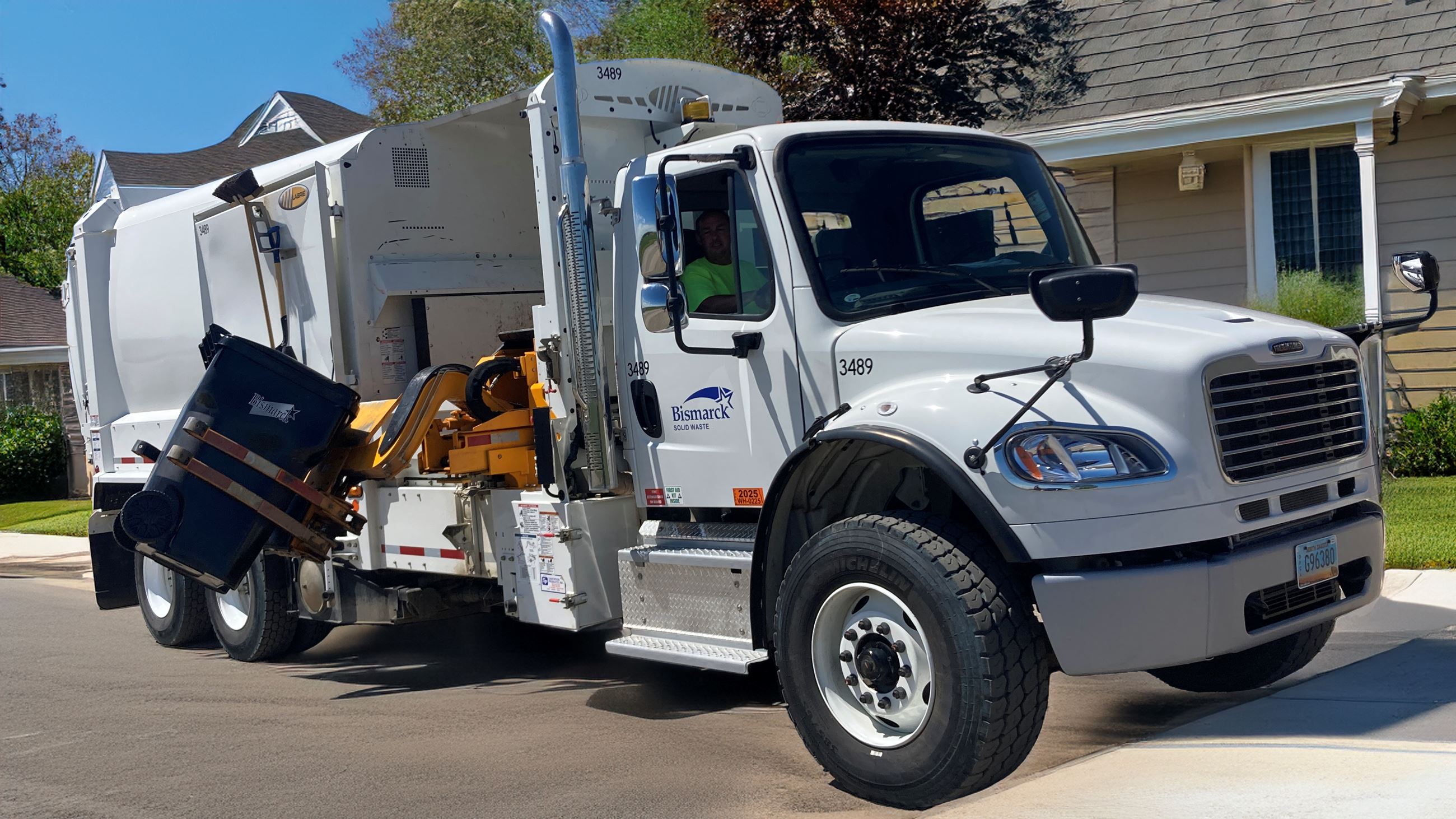 A City of Bismarck garbage truck uses a side arm to empty a garbage can. 