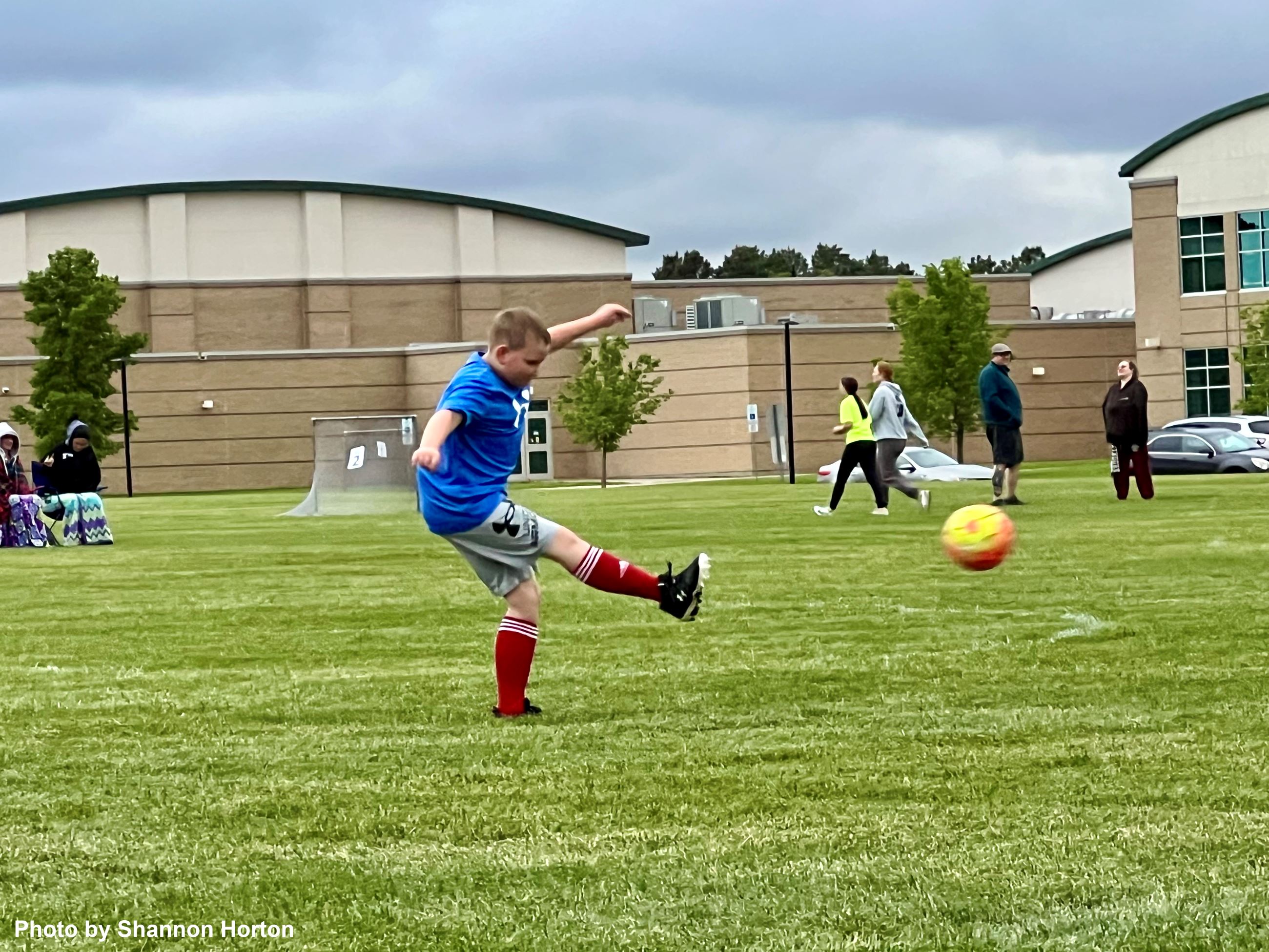 A boy kicking a soccer ball at a goal. 