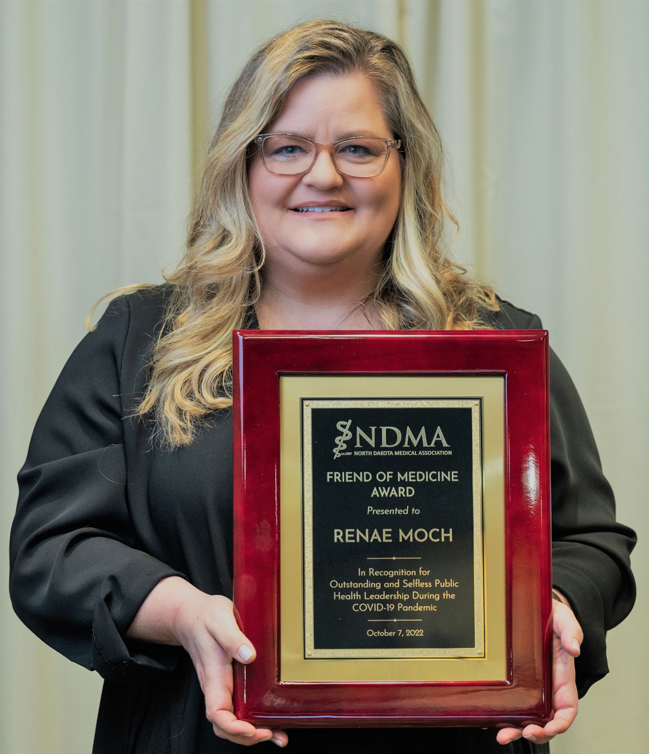 Renae Moch holding Friend of Medicine award. 